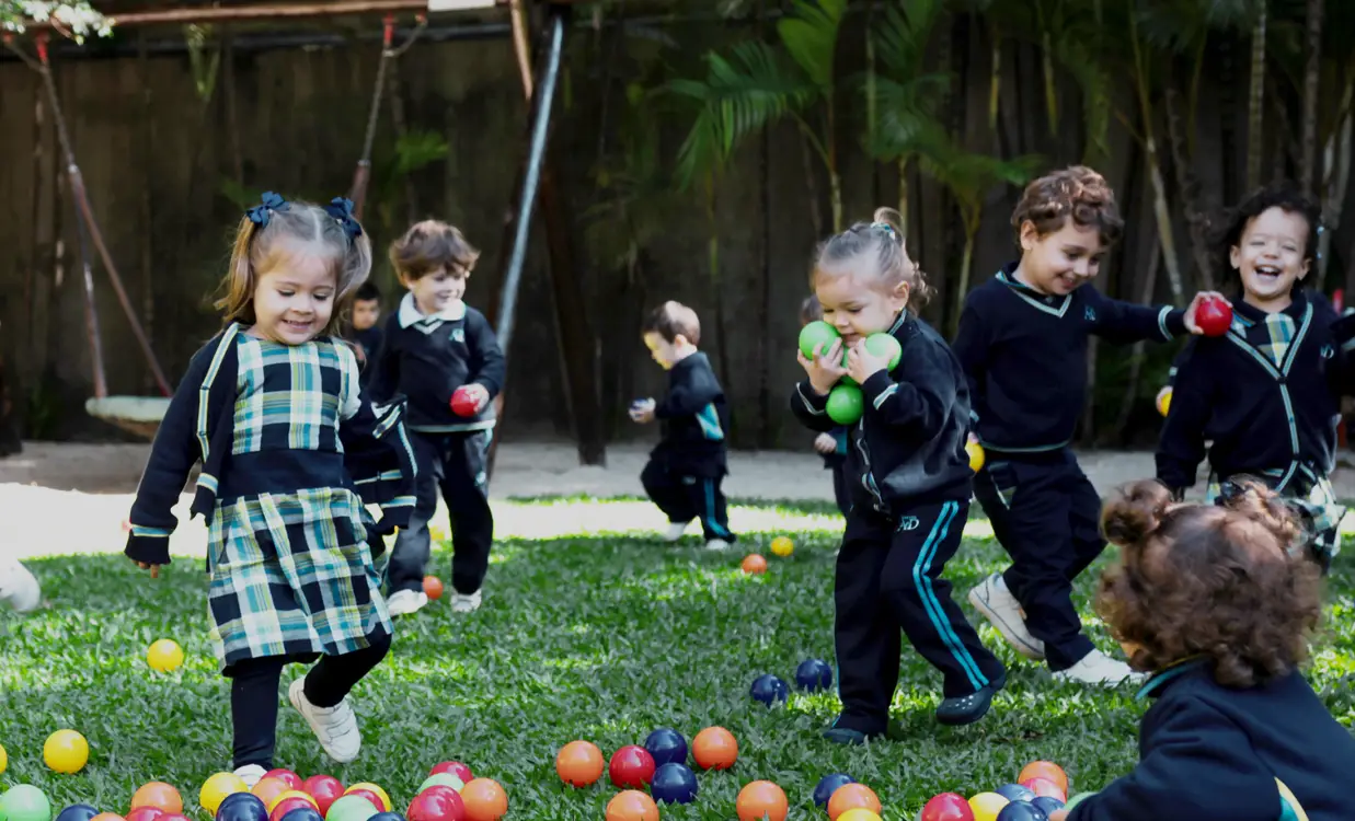 Crianças brincando com bolinhas coloridas de plástico.